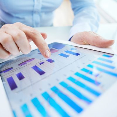 Image of human hand pointing at touchscreen with business document