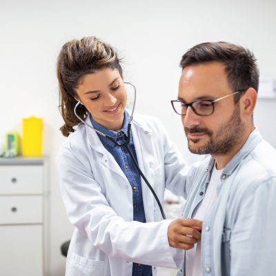 Young doctor is using a stethoscope listen to the heartbeat of the patient. Shot of a female doctor giving a male patient a check up