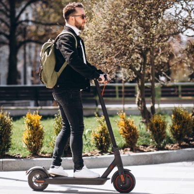 Young handsome man riding on scooter in the park